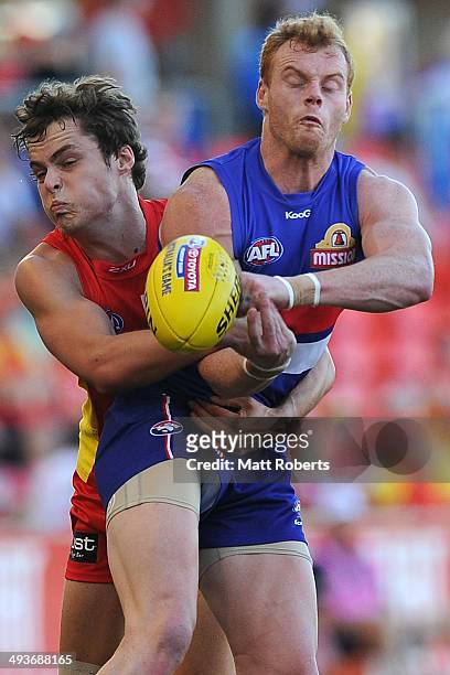 Adam Cooney of the Bulldogs handbalsl in the tackle by Kade Kolodjashnij of the Suns during the round 10 AFL match between the Gold Coast Suns and...