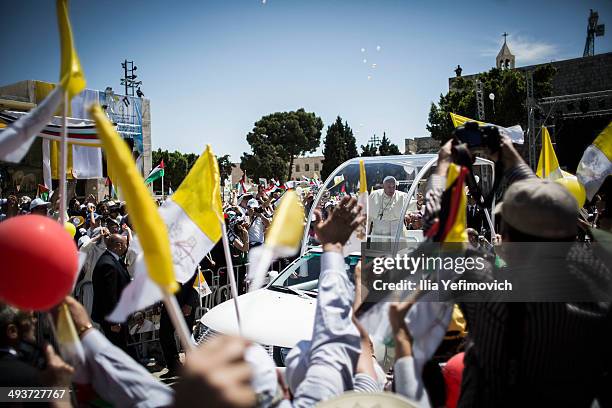 Pope Francis arrives in Manger Square to take part in a Mass held at the Church of Nativity as crowds watch and wave flags in the foreground on May...