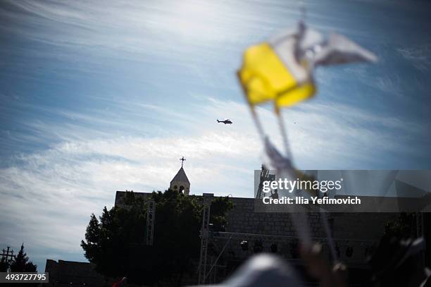 Pope Francis flies over the square in a helicopter on his way to Manger Square to take part in a Mass held at the Church of Nativity as crowds watch...