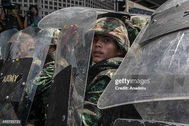 Military soldiers stand guard as anti-coup protesters take part in a rally in front of Amarin Plaza at Ratchaprasong intersection in the capital...