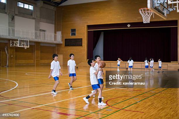 japanese children practising basketball in the school gymnasium - grand prix of japan practice stockfoto's en -beelden