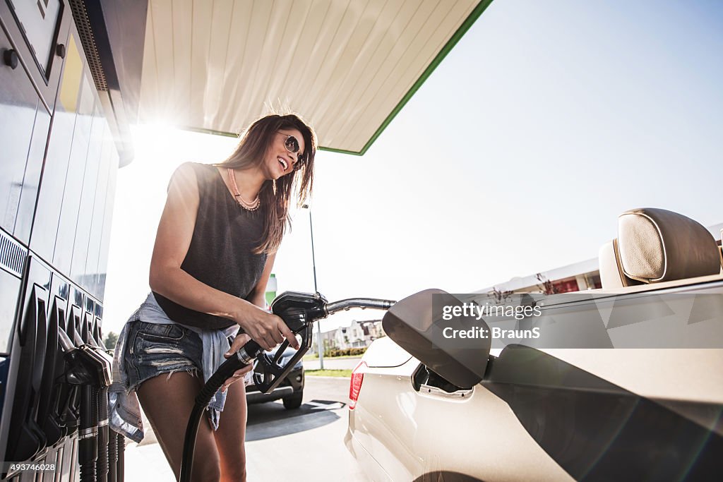 Low angle view der glückliche Frau an der Tankstelle.