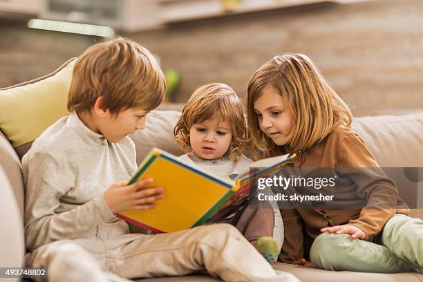 niños leyendo libro de imágenes en su hogar. - fairytale fotografías e imágenes de stock