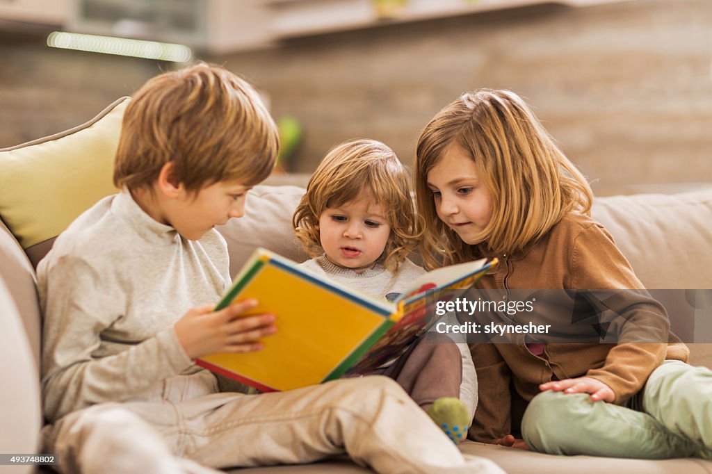 Children reading picture book at home.