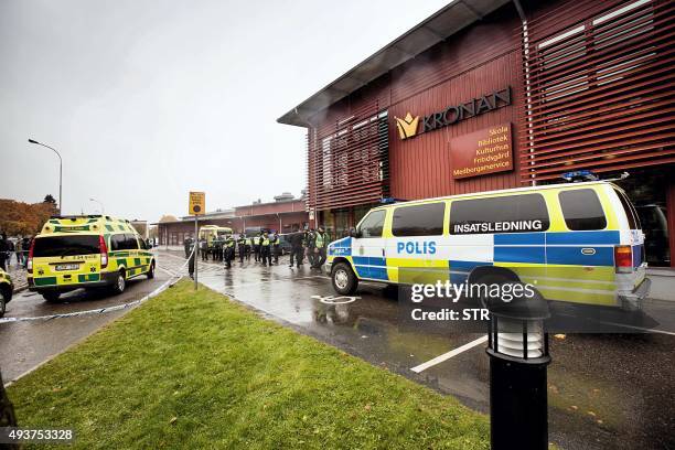 Police vans are parked in front of the primary and middle school Kronan in Trollhattan, southwestern Sweden, on October 22 where a masked man armed...