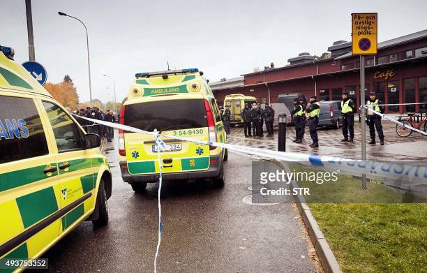 Police vans are parked in front of the primary and middle school Kronan in Trollhattan, southwestern Sweden, on October 22 where a masked man armed...