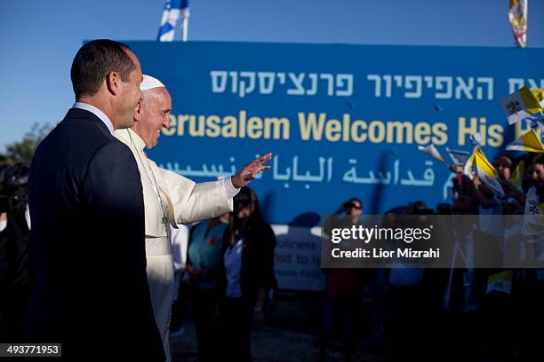 Pope Francis , accompanied by Jerusalem Mayor Nir Barkat , walks past a large banner welcoming him to Jerusalem in three languages after arriving to...