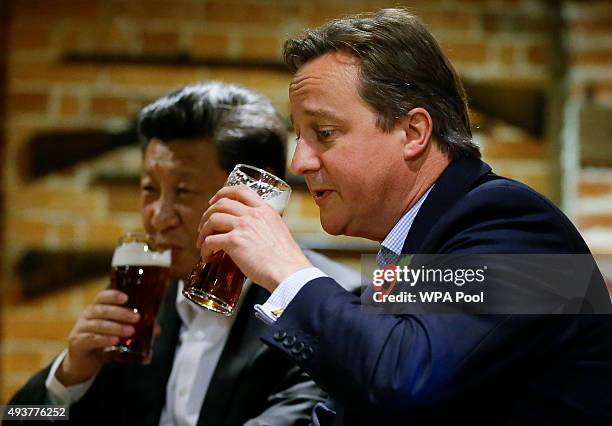 China's President Xi Jinping and Britain's Prime Minister David Cameron drink a pint of beer during a visit to the The Plough pub on October 22, 2015...