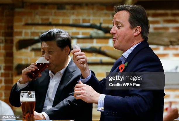 Britain's Prime Minister David Cameron gets out money to pay for drinks as China's President Xi Jinping drinks a pint of beer during a visit to the...