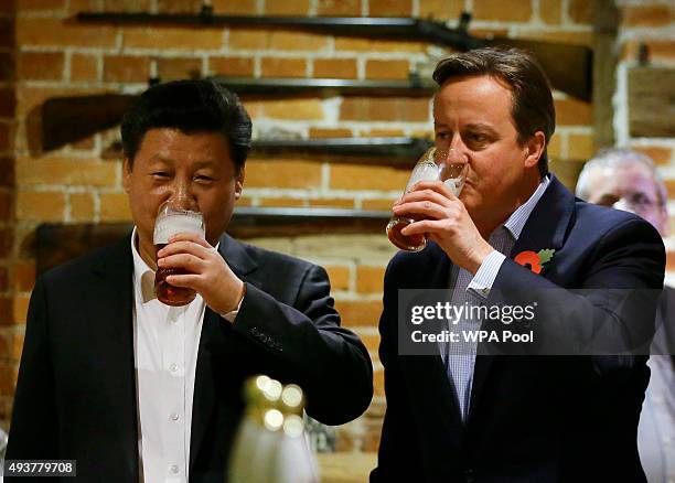 China's President Xi Jinping and Britain's Prime Minister David Cameron drink a pint of beer during a visit to the The Plough pub on October 22, 2015...