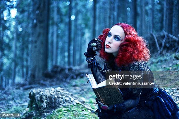 witch in the forest rading book. halloween theme - young goth girls stockfoto's en -beelden