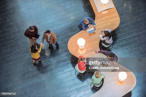 business people sitting at curved wooden desk, high angle view - above stock pictures, royalty-free photos & images