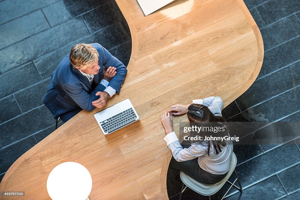 Two business people in meeting at curved desk overhead view