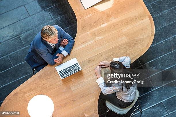two business people in meeting at curved desk overhead view - business relationship stock pictures, royalty-free photos & images