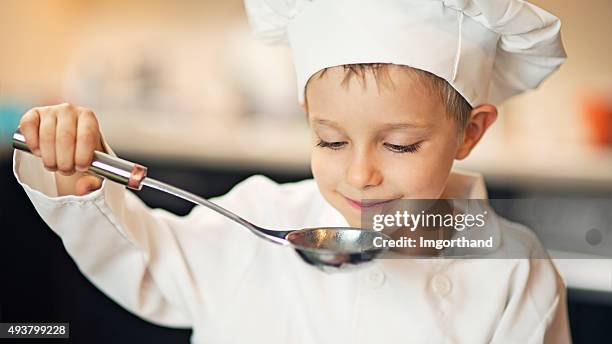 little boy chef tasting soup. - chefs whites stock pictures, royalty-free photos & images