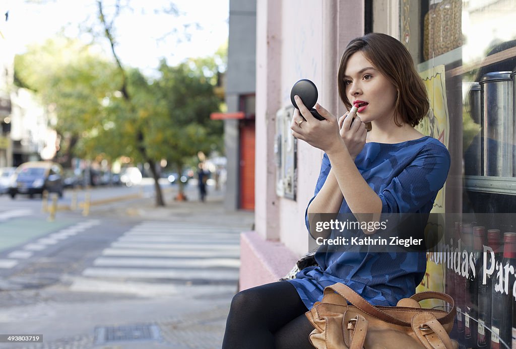 Young woman applying lipstick