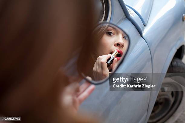 young woman applying lipstick - lipstick mirror stock pictures, royalty-free photos & images