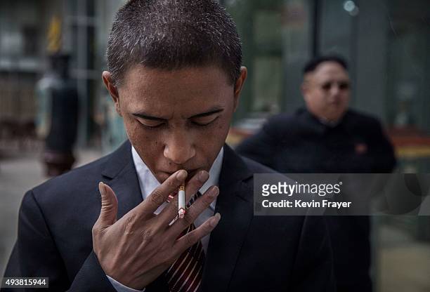 Chinese actor and United States President Barack Obama impersonator Xiao Jiguo smokes a cigarette as he and North Korean leader Kim Jung Un...