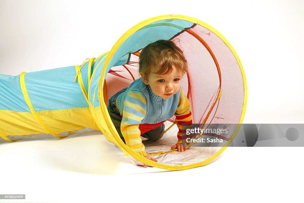 Baby boy crawling out of a tunnel toy