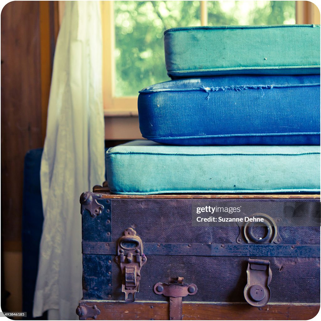 Stacked cushions and a suitcase