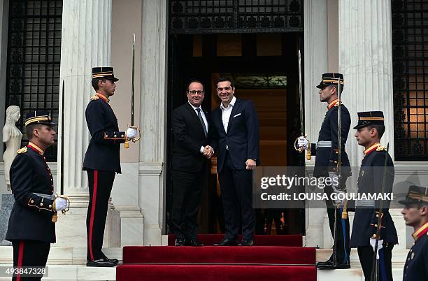 Greek prime minister Alexis Tsipras welcomes French President Francois Hollande prior to their talks at Tsipras' office in Athens on October 23,...