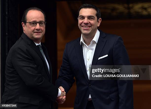 Greek prime minister Alexis Tsipras welcomes French President Francois Hollande prior to their talks at Tsipras' office in Athens on October 23,...