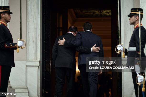 Greek prime minister Alexis Tsipras and French President Francois Hollande hold each other while they proceed to Tsipras' office for their talks in...