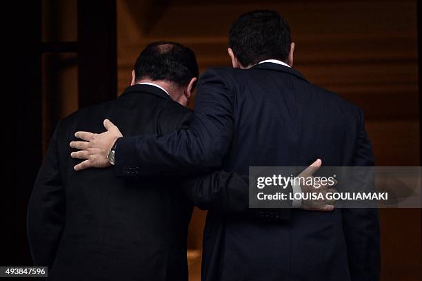 Greek prime minister Alexis Tsipras and French President Francois Hollande hold each other while they proceed to Tsipras' office for their talks in...