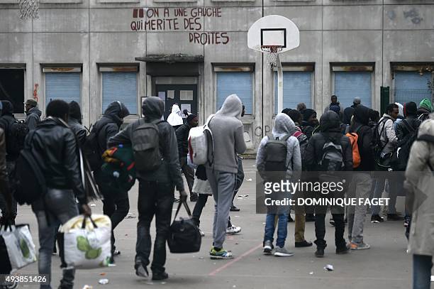 Migrants wait as they prepare to leave their makeshift camp after being evicted by the French authorities from a camp set in a disused school on...