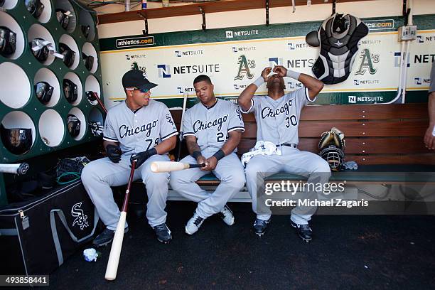 Jose Abreu, Dayan Viciedo and Alejandro De Aza of the Chicago White Sox relax in the dugout prior to the game against the Oakland Athletics at O.co...