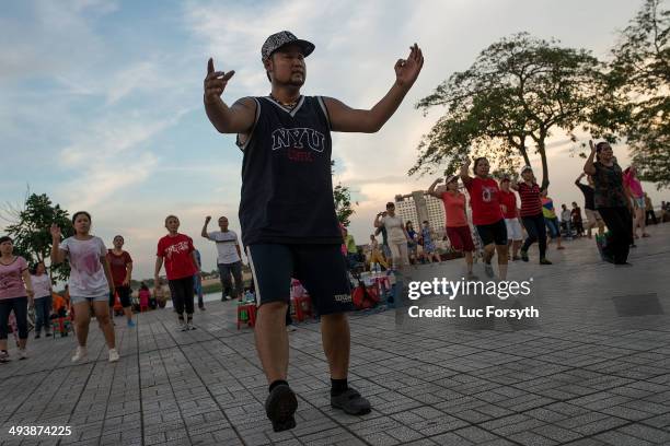 An instructor leads a public aerobic dance class along Phnom Penh's riverside on May 25, 2014 in Phnom Penh, Cambodia. Cambodians remain...
