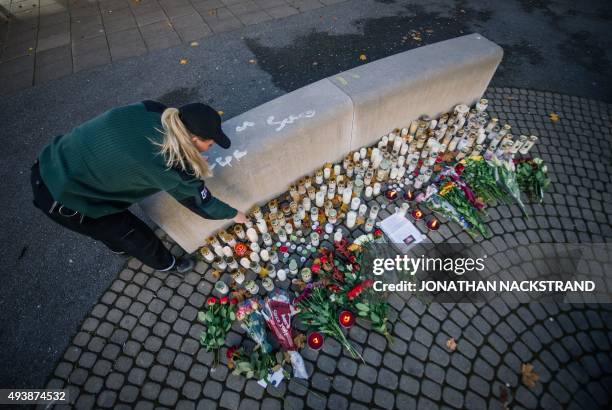 Woman lights candles outside the primary and middle school Kronan in Trollhattan, southwestern Sweden, on October 23 where a masked man armed with a...