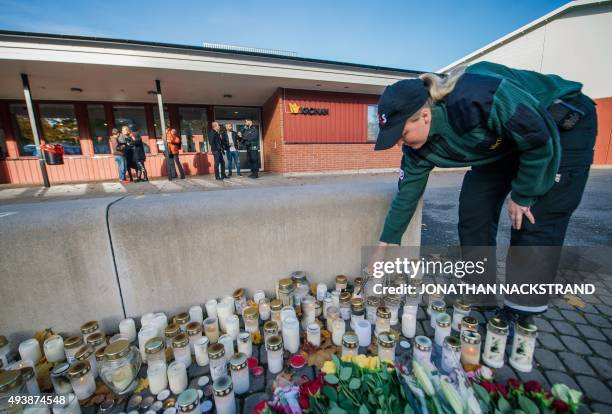 Woman lights candles outside the primary and middle school Kronan in Trollhattan, southwestern Sweden, on October 23 where a masked man armed with a...