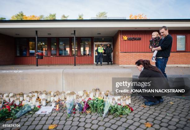 Woman lights a candle outside the primary and middle school Kronan in Trollhattan, southwestern Sweden, on October 23 where a masked man armed with a...