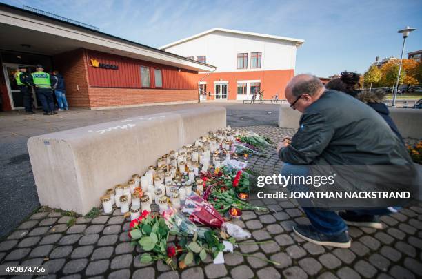 Man lights a candle outside the primary and middle school Kronan in Trollhattan, southwestern Sweden, on October 23 where a masked man armed with a...