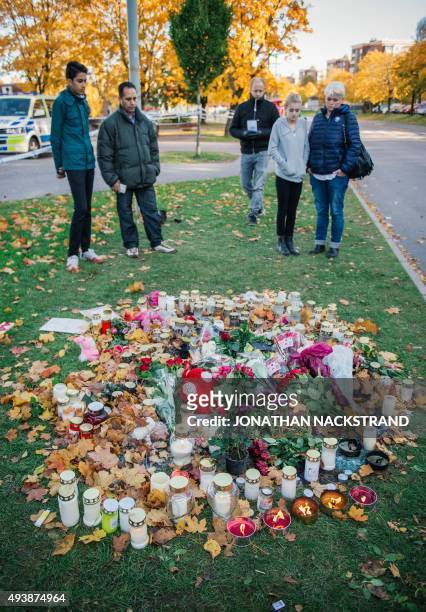 People stand by candles and flowers outside the primary and middle school Kronan in Trollhattan, southwestern Sweden, on October 23 where a masked...