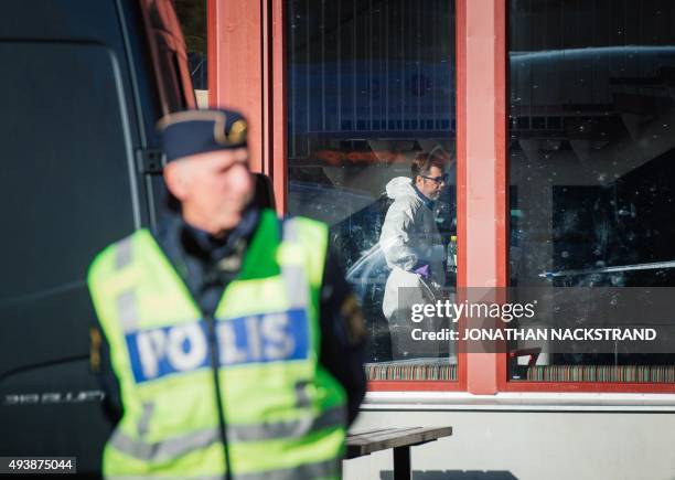 Police officers guard as a forensic staff investigates inside the primary and middle school Kronan in Trollhattan, southwestern Sweden, on October 23...