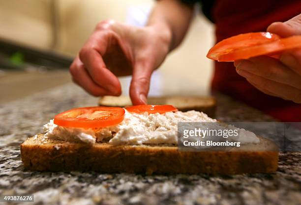 An employee places sliced tomatoes on to a fresh chicken bloomer sandwich in a Greggs Plc sandwich chain outlet in Caterham, U.K., on Thursday, Oct....