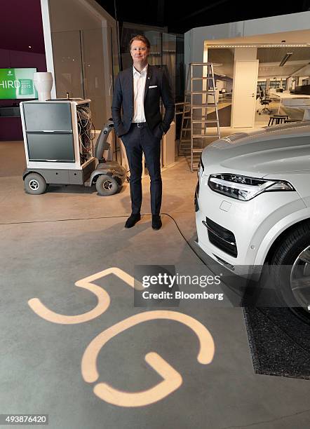 Hans Vestberg, chief executive officer of Ericsson AB, poses for a photograph beside a 5G base station prototype, left, and a Volvo Cars XC90...