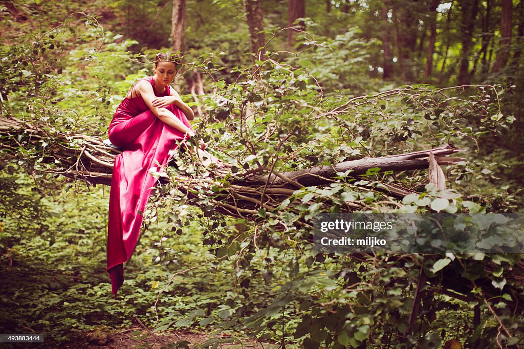 Mode model in lange satin-Kleid sitzt auf alten Holz