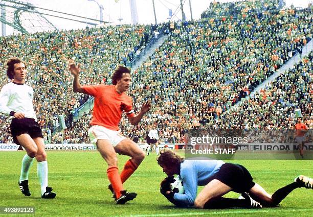 West German goalkeeper Sepp Maier catches the ball in front of Dutch forward Johan Cruyff as defender Franz Beckenbauer looks on, 07 July 1974 in...