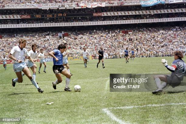 Argentinian forward Diego Armando Maradona runs past English defender Terry Butcher on his way to dribbling goalkeeper Peter Shilton and scoring his...