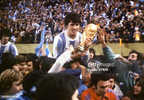 Argentine's national soccer team captain Daniel Passarella holds the World Cup trophy as he is carried on the shoulders of fans after Argentina...