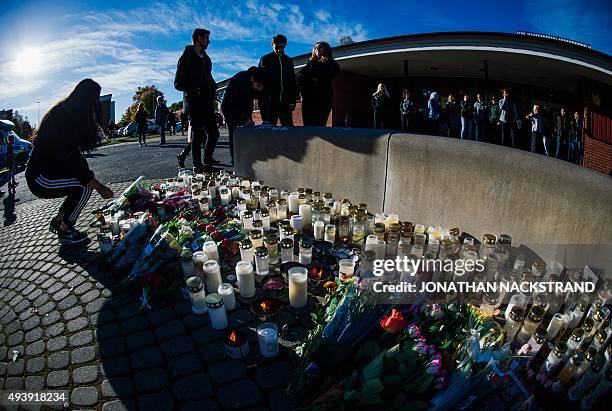 Woman lights candles outside the primary and middle school Kronan in Trollhattan, southwestern Sweden, on October 23 where a masked man armed with a...