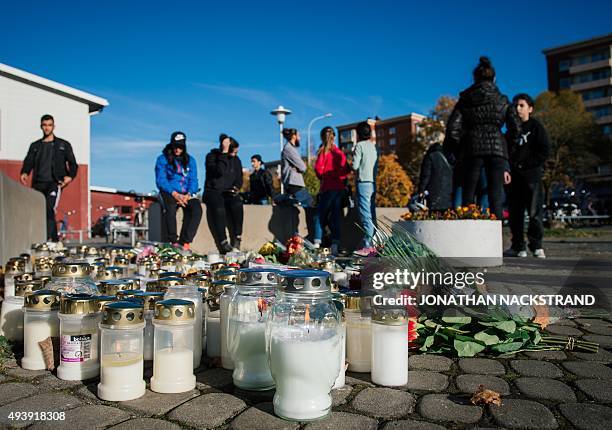 People stand by candles and flowers outside the primary and middle school Kronan in Trollhattan, southwestern Sweden, on October 23 where a masked...