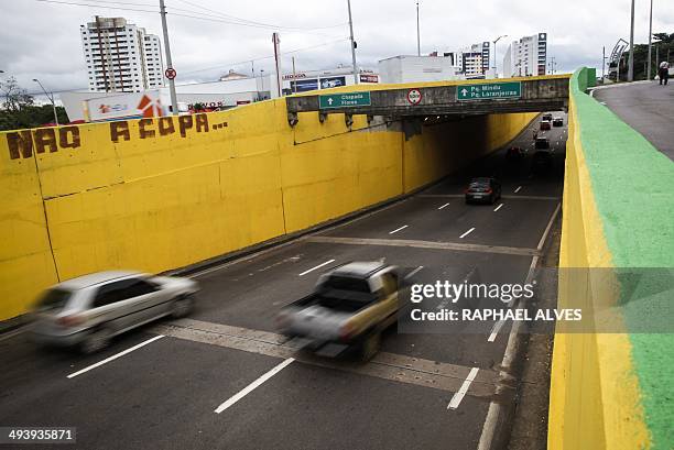 Cars drive along a level crossing painted in yellow and green for the upcoming FIFA World Cup on which a graffiti reading "No to the World Cup" was...