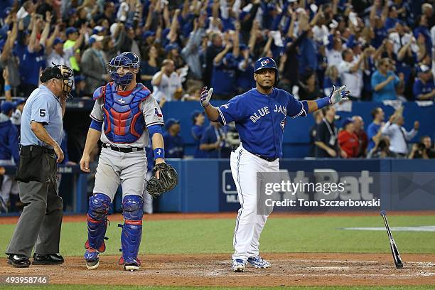 Edwin Encarnacion of the Toronto Blue Jays reacts as he hits a game-tying solo home run in the sixth inning as Chris Gimenez of the Texas Rangers and...