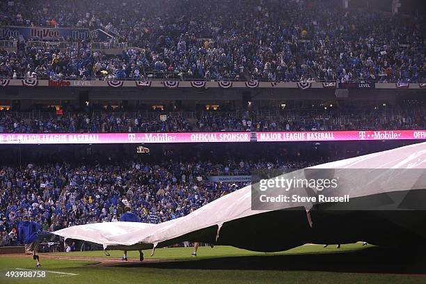 The tarp rolls out as rain starts falling in the eighth inning. The Toronto Blue Jays and the Kansas City Royals play game five of the MLB American...