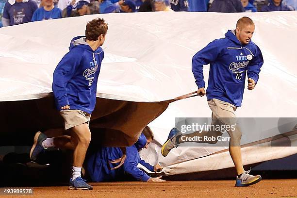 Members of the groundcrew bring a tarp out on the field as one falls down in the eighth inning in game six of the 2015 MLB American League...