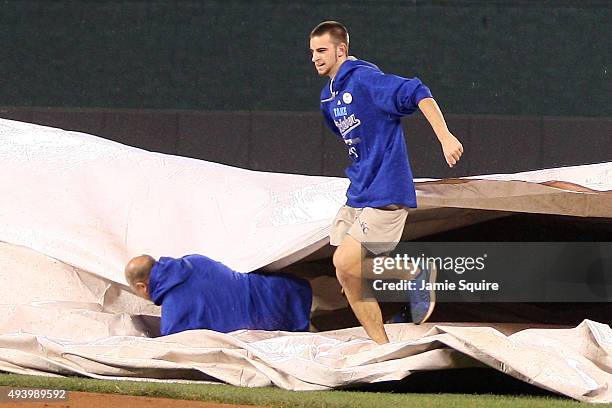 Members of the groundcrew bring a tarp out on the field as one falls down in the eighth inning in game six of the 2015 MLB American League...